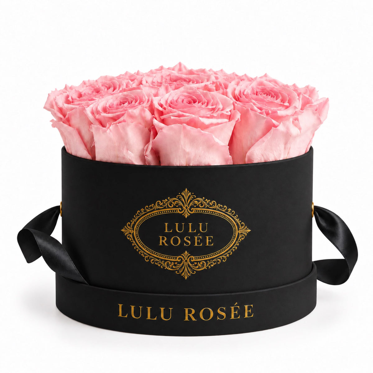 Light pink preserved roses in a black small round box on a white background.
