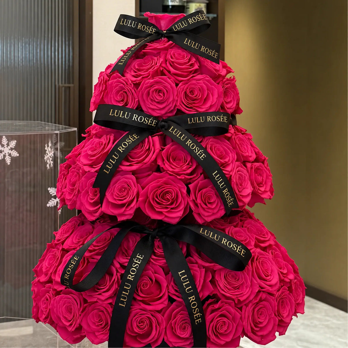 Close view of hot pink preserved roses and black branded ribbons on a Christmas tree arrangement