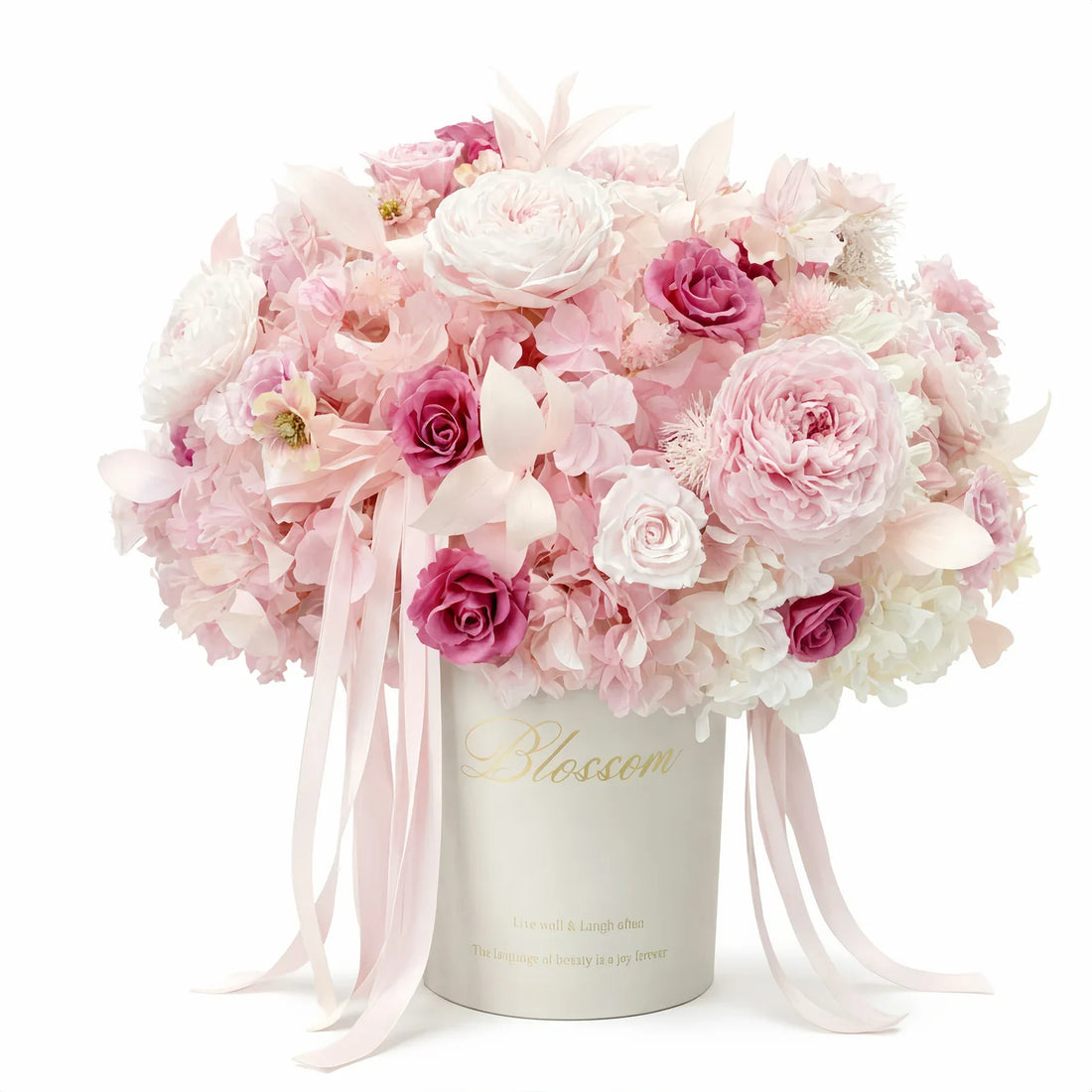 Blush-pink preserved roses and hydrangeas in a bucket-style arrangement.