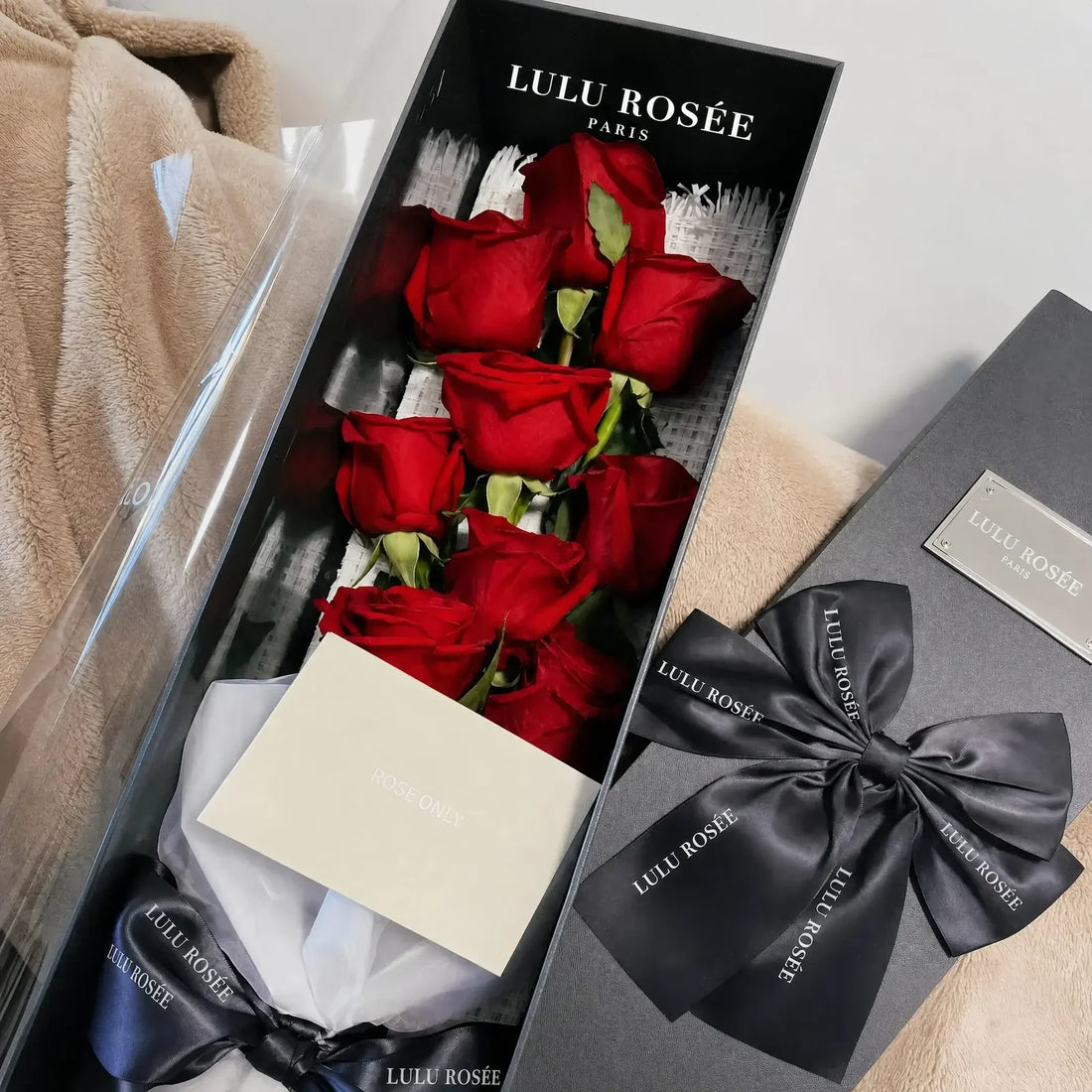 Nine red long-stem preserved roses presented in an open gift box with a greeting card.