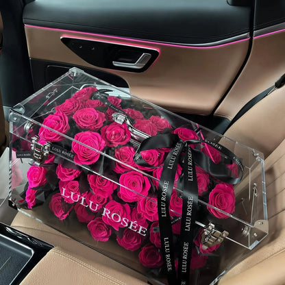 LULU ROSÉE Grande Eternal Acrylic Handbag Rose Box, luxury handbag-shaped transparent acrylic gift box filled with rosy preserved roses, car interior lifestyle shot, customizable flower colors, romantic everlasting floral souvenir for anniversary & birthday gifting