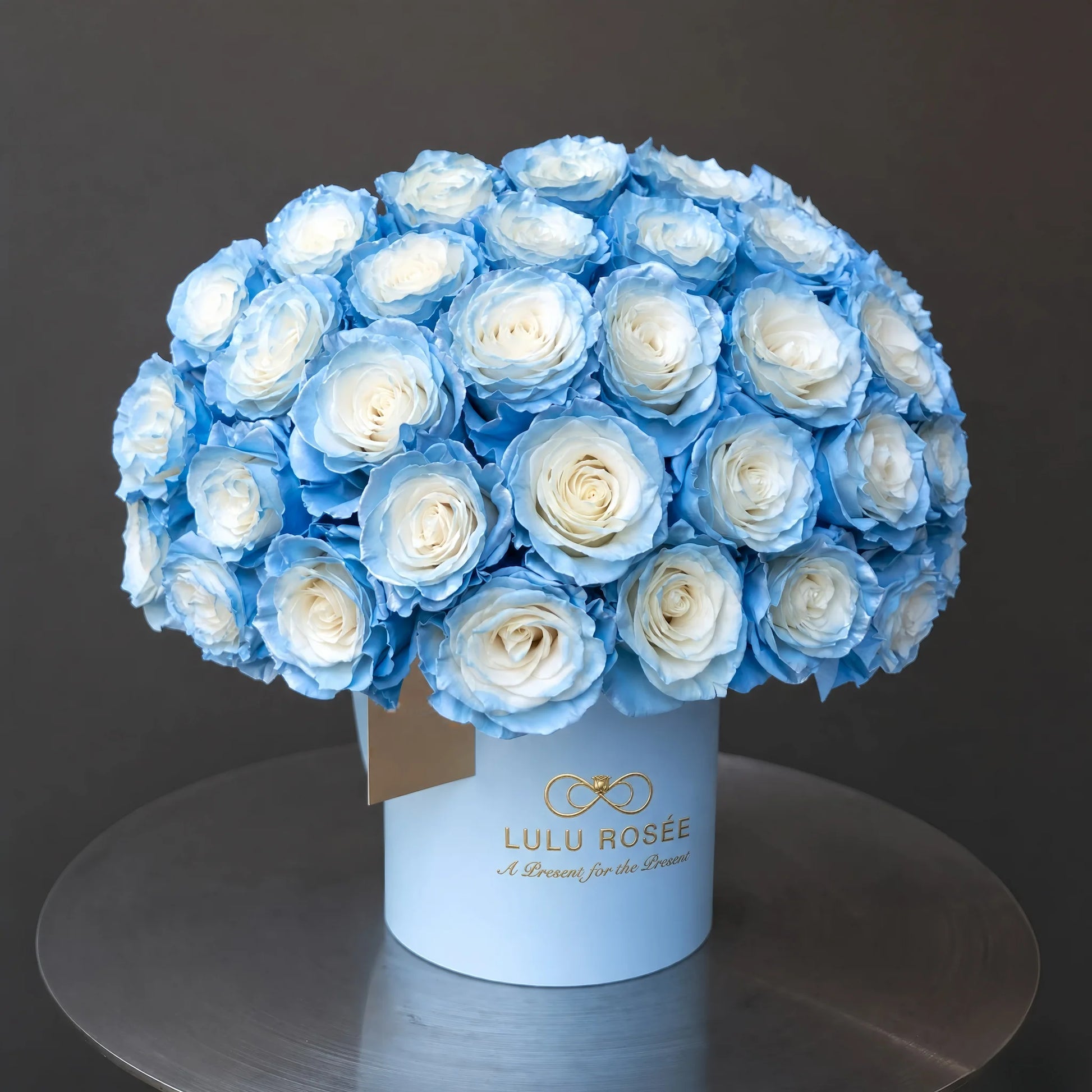 LULU ROSÉE Grande Superdome Ice Blue Gradient Preserved Rose Box, angled overhead shot of lush dome-shaped ice blue gradient preserved roses in light blue cylinder box