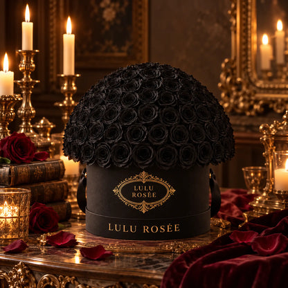 Black preserved roses in a black LULU ROSÉE Large Le Plein box in a candlelit setting.