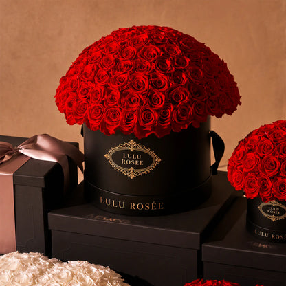 Red preserved roses in a black LULU ROSÉE Large Le Plein box in a luxury gift setting.