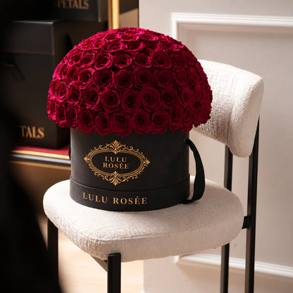 Red preserved roses in a black LULU ROSÉE Large Le Plein box in a lounge setting.