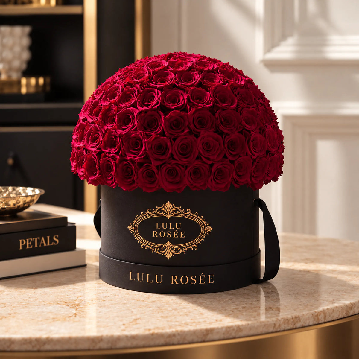 Red preserved roses in a black LULU ROSÉE Large Le Plein box displayed in a refined interior.