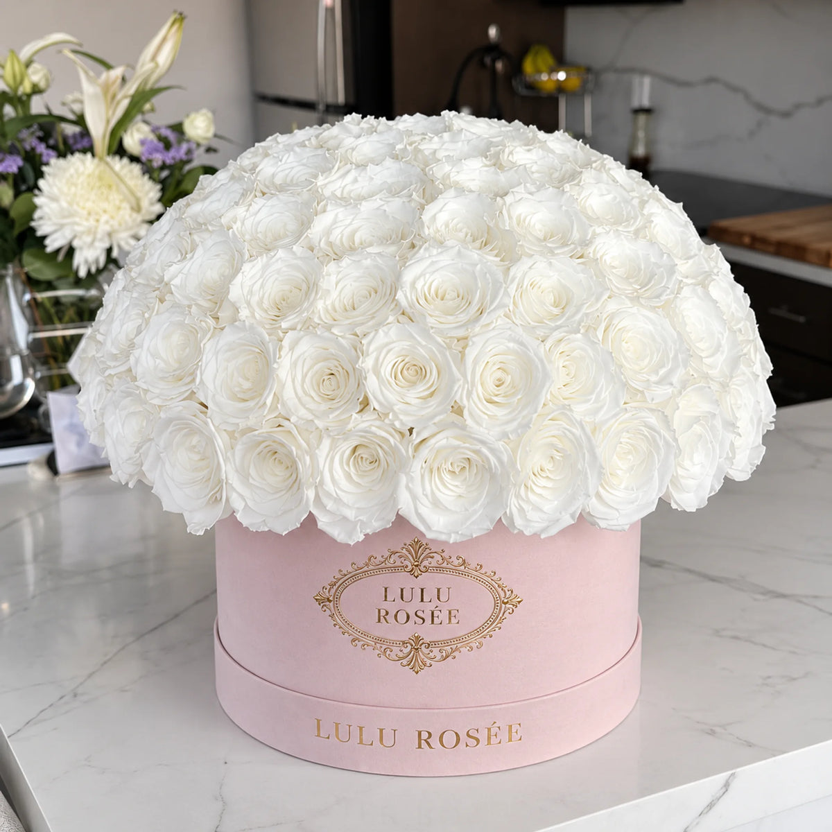 White preserved roses in a blush LULU ROSÉE Large Le Plein box in an elegant room.