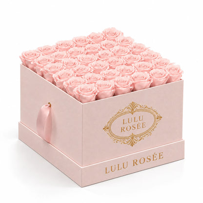 Blush preserved roses in a blush suede LULU ROSÉE large square box, photographed against a soft neutral backdrop.
