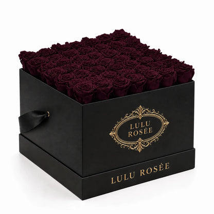 Deep burgundy preserved roses fill a black classic LULU ROSÉE large square box on a white background.