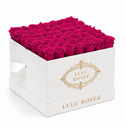 Hot pink preserved roses arranged in a white classic LULU ROSÉE large square box against a clean white background.