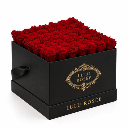 Red preserved roses fill a black classic LULU ROSÉE large square box, photographed from the front against a white background.