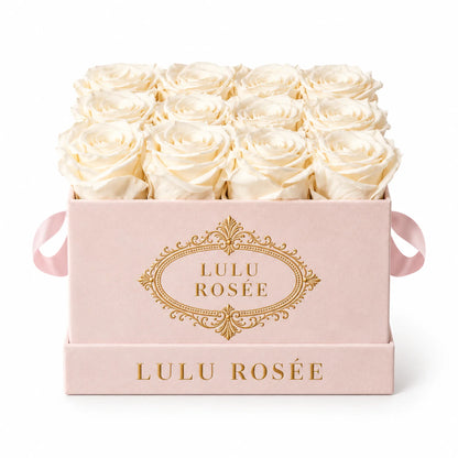 White preserved roses in a blush suede LULU ROSÉE medium square box on a white background.
