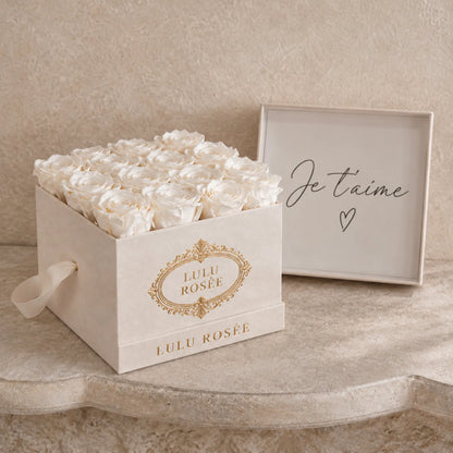 White preserved roses in a cream suede LULU ROSÉE medium square box, french setting.
