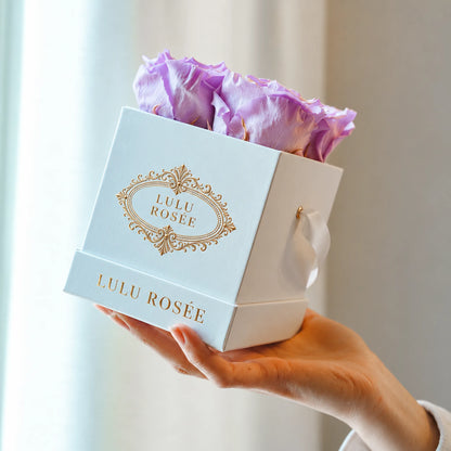White classic box with light purple preserved roses, held in a hand