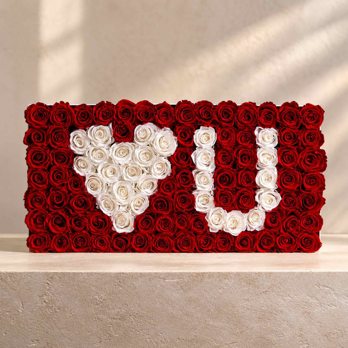 Red and white preserved roses arranged in a rectangular monogram display