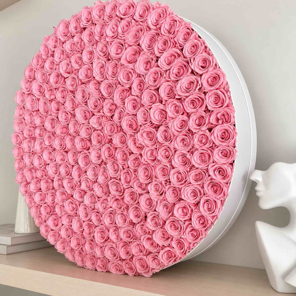 A grand light pink preserved rose arrangement displayed beside sculptural decor