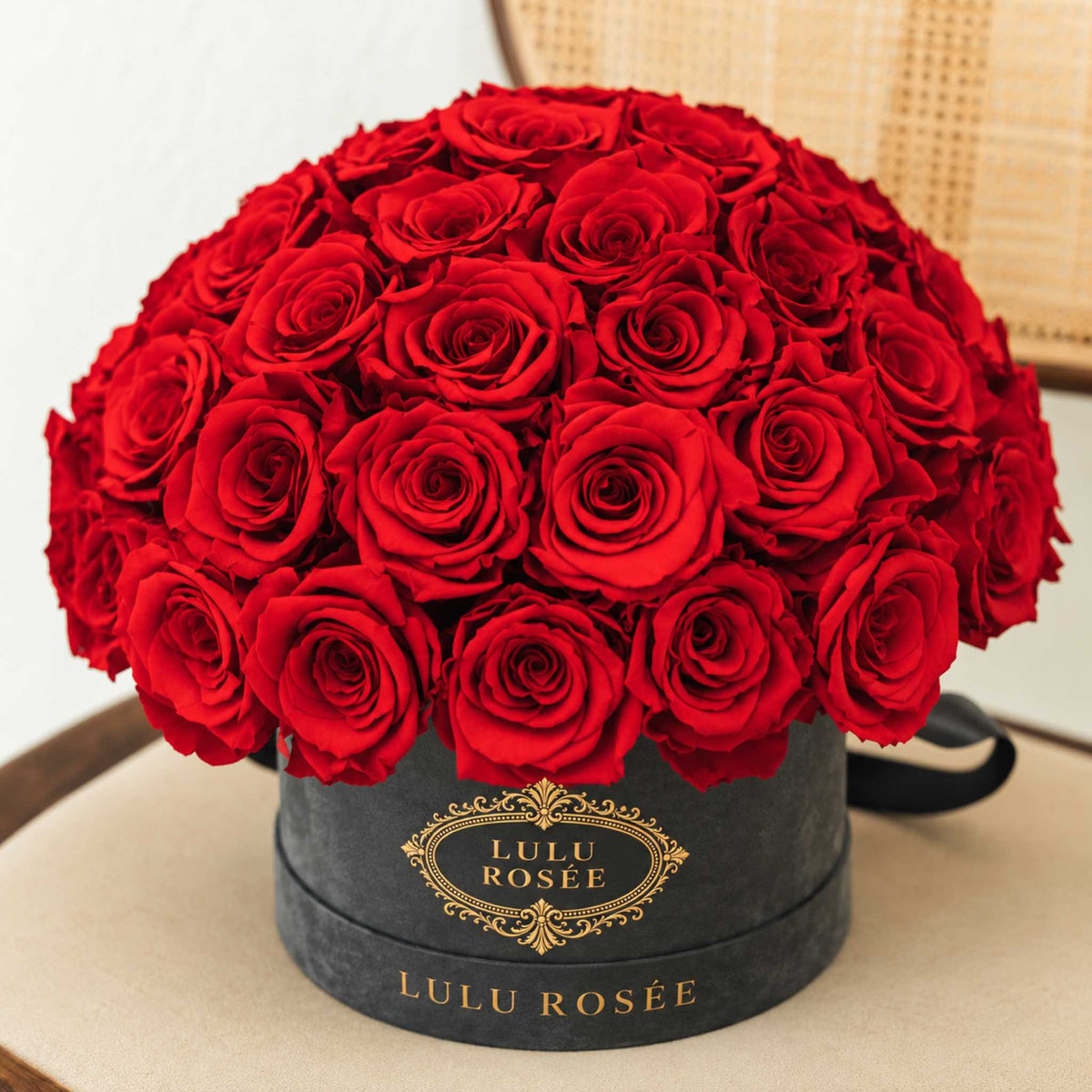 Red preserved roses in a grey suede Small Le Plein box in an interior setting.