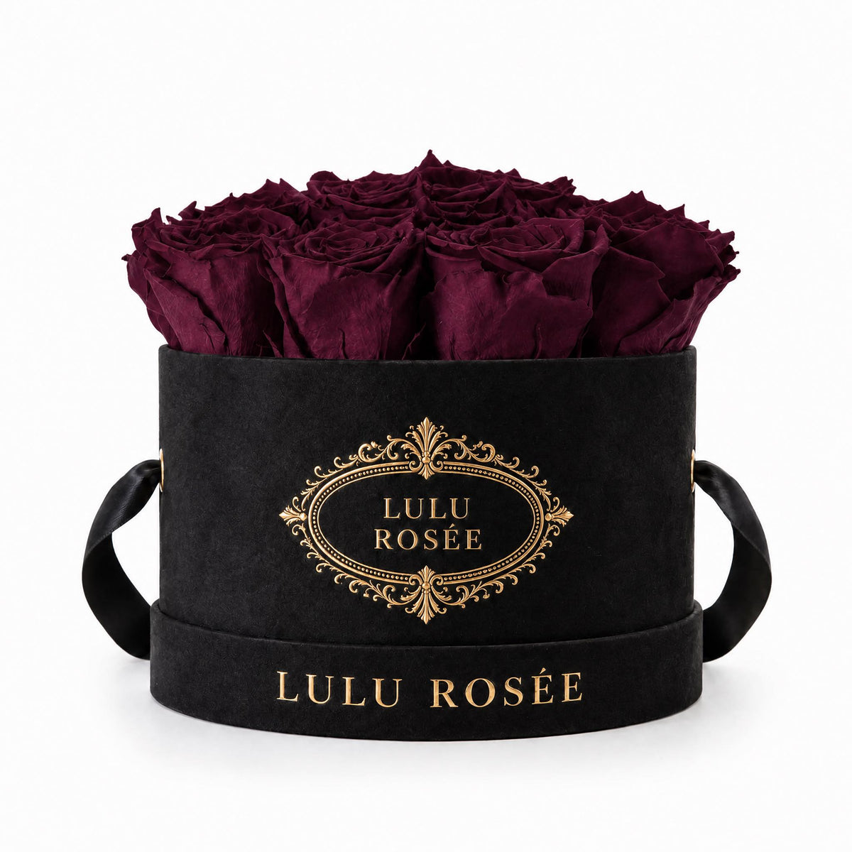 Burgundy preserved roses in a black small round box on a white background.