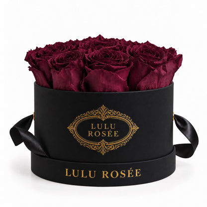 Burgundy preserved roses in a black round box with a black ribbon.