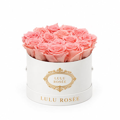 Light pink preserved roses in a white round box with a gold LULU ROSÉE logo.