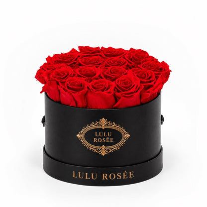 Red preserved roses in a black round box with a gold LULU ROSÉE logo.