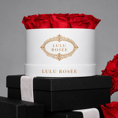 Red preserved roses in a white LULU ROSÉE round box styled with black gift boxes.