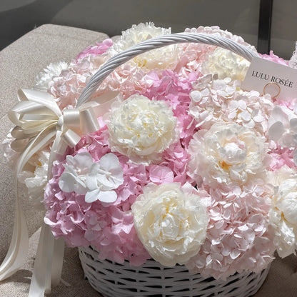 Cream bow beside white preserved peonies and blush hydrangeas in a flower basket