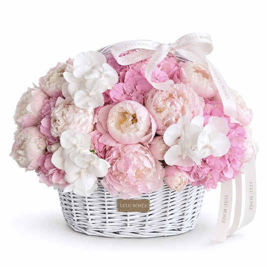 Blush preserved peony and hydrangea basket with white orchids on a white background