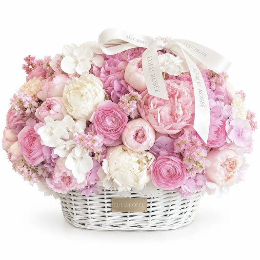 Blush preserved peony, rose and hydrangea basket with white orchids on a white background