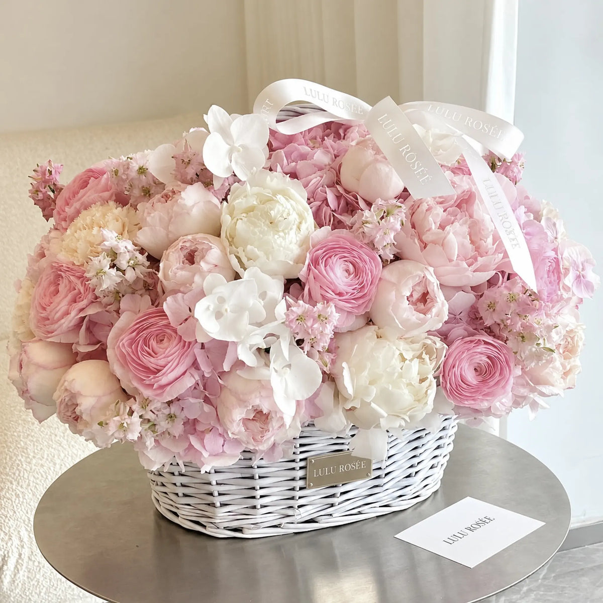 Angled view of a blush preserved flower basket with white orchid accents