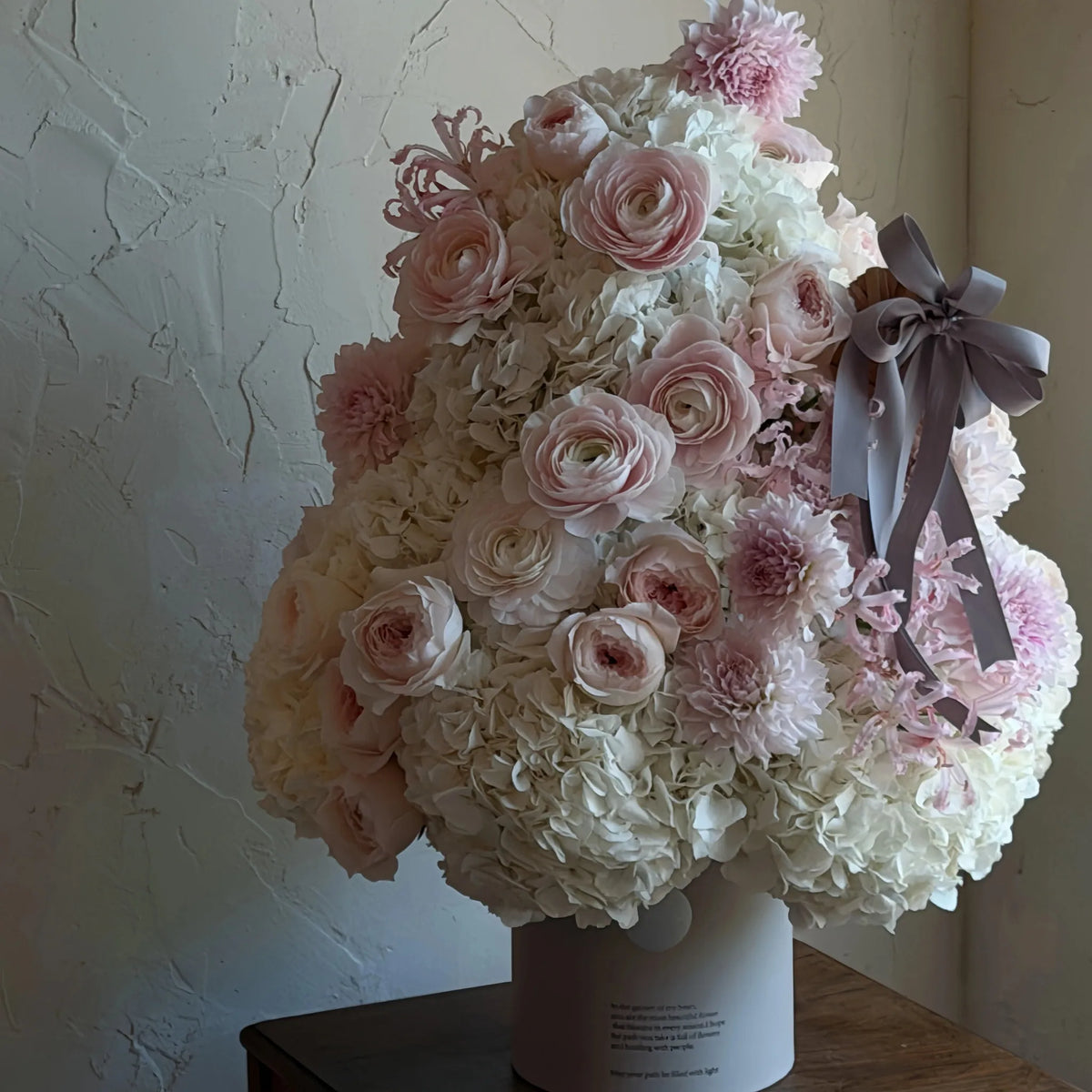 Close view of a blush and white preserved flower tree with a gray ribbon