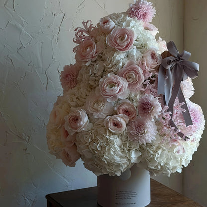 Close view of a blush and white preserved flower tree with a gray ribbon