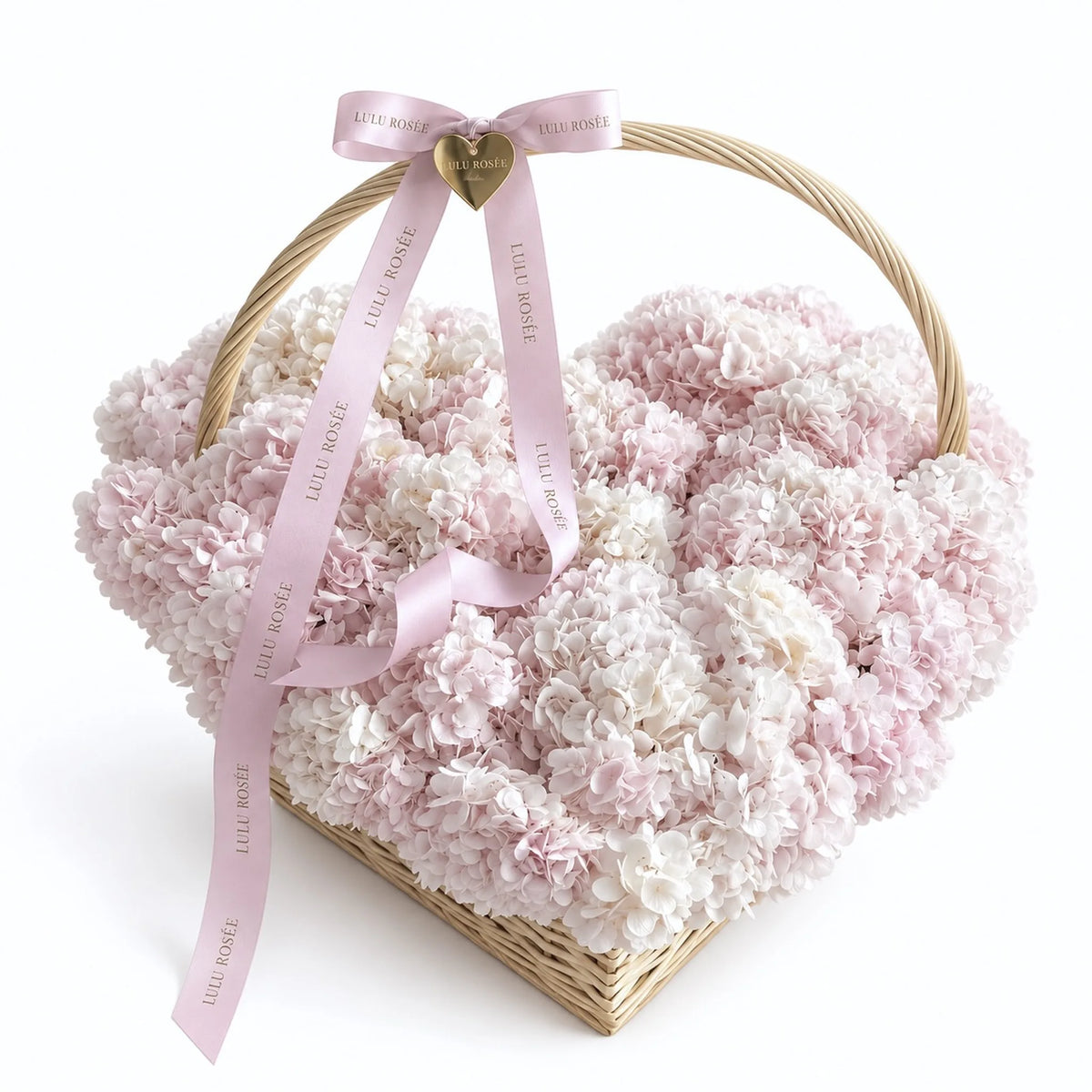 Blush and white preserved hydrangeas in a heart-shaped handled basket with pink ribbons