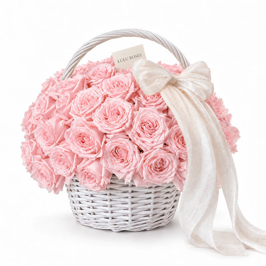 Blush preserved roses in a white basket with a long white ribbon