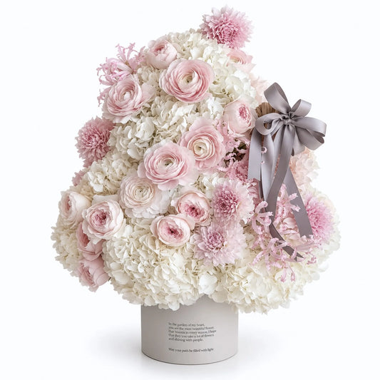 Blush and white preserved flower Christmas tree with a gray bow on a white background