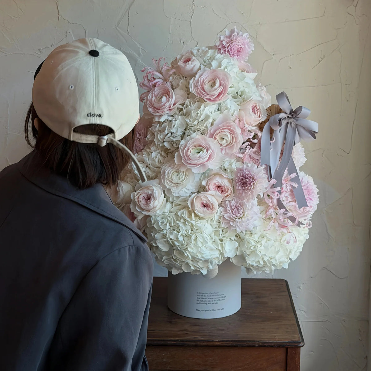 Preserved Christmas flower arrangement shown beside a person in an interior setting
