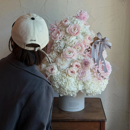 Preserved Christmas flower arrangement shown beside a person in an interior setting