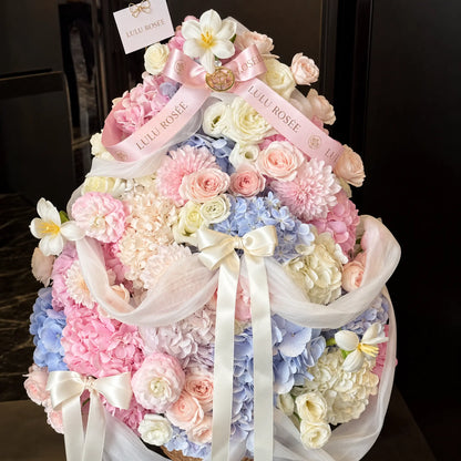 Front view of a Christmas inspired preserved flower arrangement with cascading white ribbons