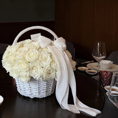 Cream preserved rose basket with a white ribbon displayed on a dining table