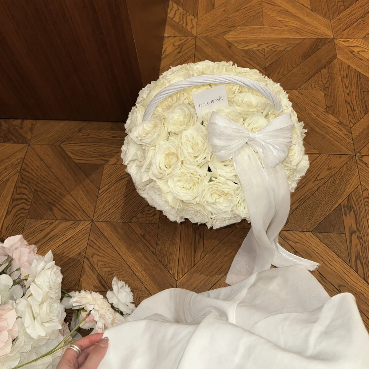 Overhead view of a cream preserved rose basket with a white bow