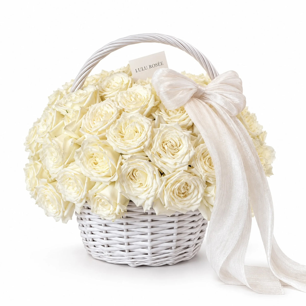 Cream preserved roses in a white handled basket with a flowing white bow