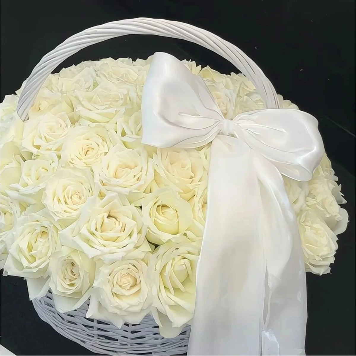 Close view of cream preserved roses and a white bow in a handled basket