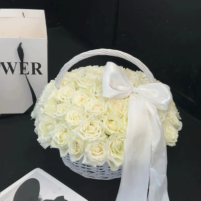 Cream preserved rose basket with a white bow against a dark background