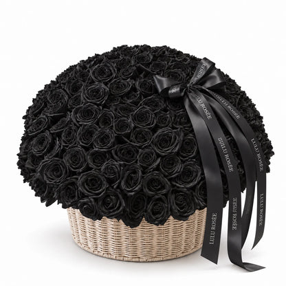 Black preserved roses in a round basket with a flowing black bow