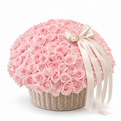 Blush preserved rose arrangement in a round basket with a white ribbon