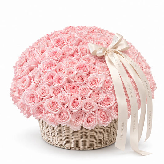 Blush preserved rose arrangement in a round basket with a white ribbon