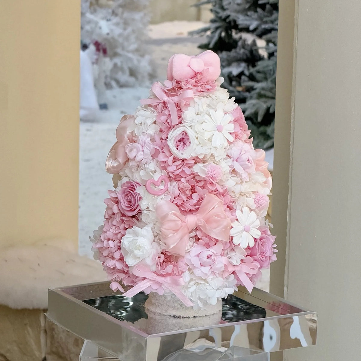 Side view of a pink and white preserved hydrangea Christmas tree on a mirrored base.