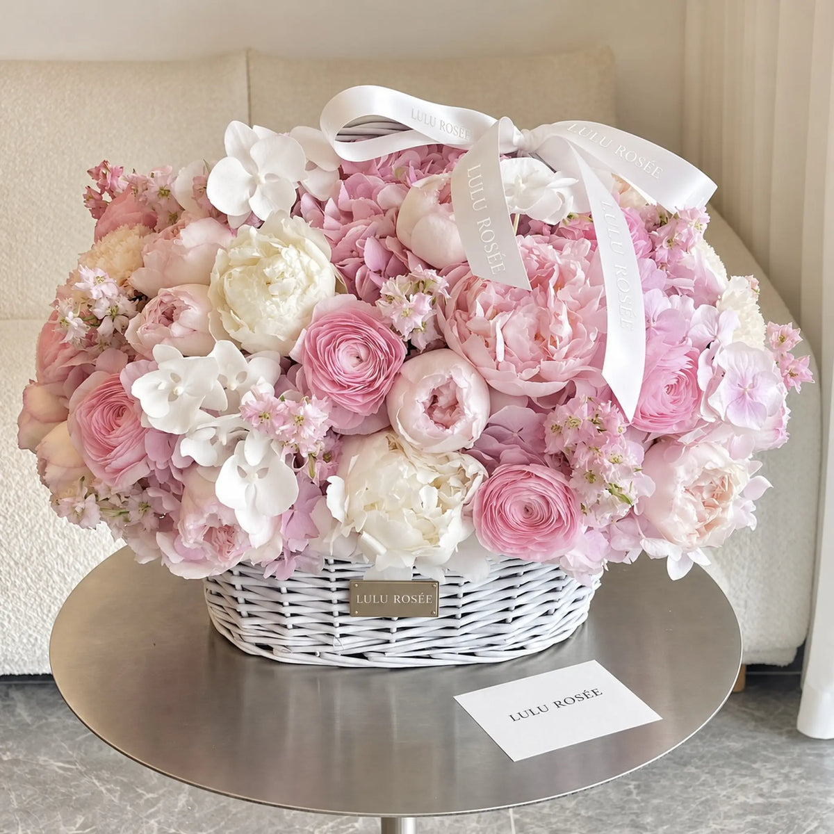 Preserved peony and hydrangea basket displayed on a table beside a LULU ROSÉE card