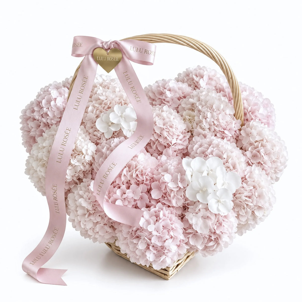 Petite blush preserved hydrangea heart basket with a curved handle and pink ribbons on a white background