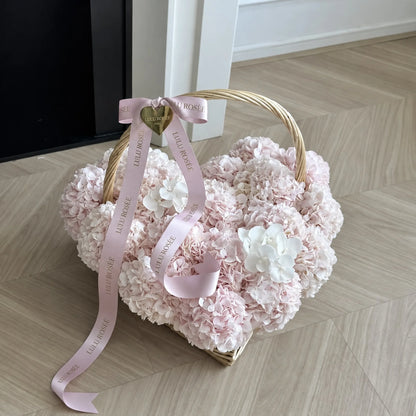 Pink ribbons draped over a petite preserved hydrangea heart basket